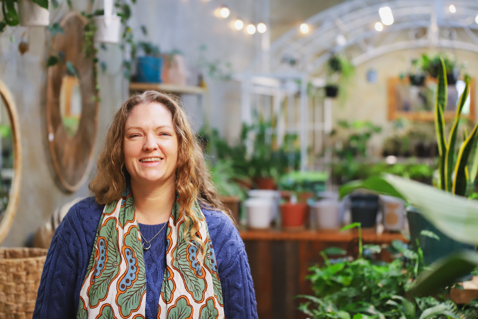 Solar for Business Selvatica Solar Superhero web card Woman with blonde hair smiling at camera in leafy green cafe